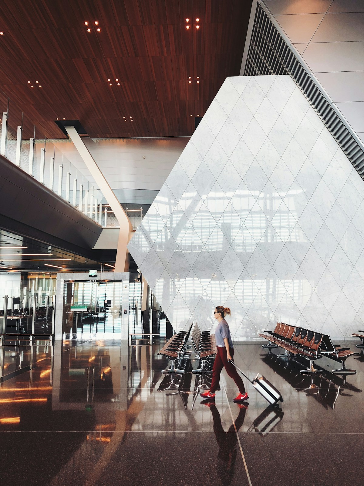 Traveler walking through a bright airport terminal with a rolling suitcase